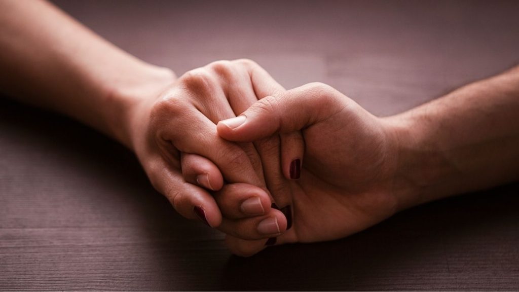 close-up van een man en een vrouw die handen vasthouden