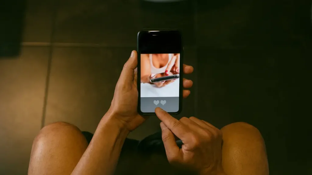 persoon die in het donker zit en druk bezig is op zijn mobiel