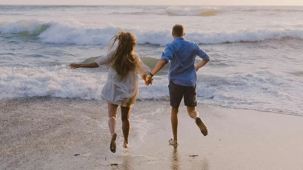 man en vrouw rennen naar de oceaangolven