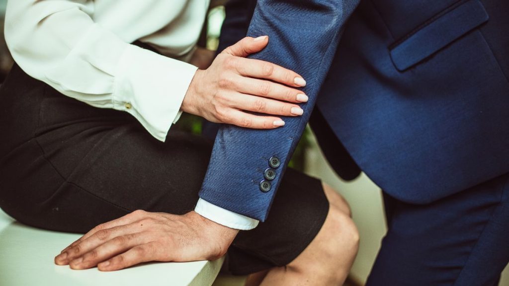 zakenvrouw die op intieme wijze de arm van een zakenman aanraakt