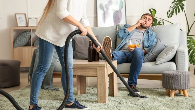 man die tv kijkt terwijl zijn vrouw stofzuigt