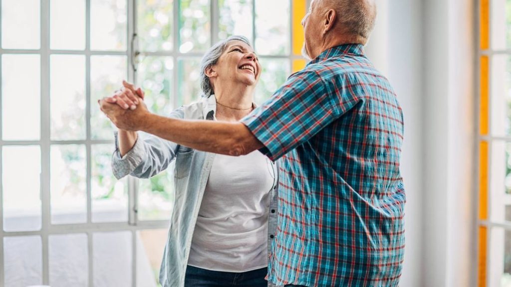 man en vrouw die vrolijk dansen in hun woonkamer