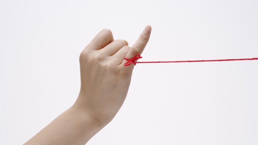 Een rood touwtje vastgebonden aan een beloftevinger als symbool voor radicaal eerlijkheid