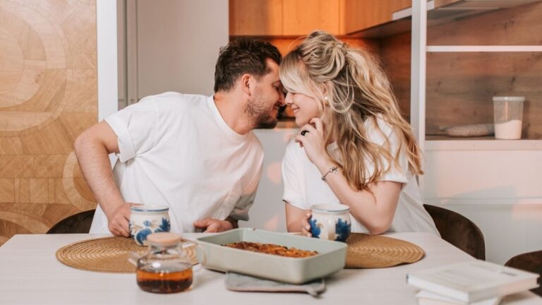 Een verliefd stel zit aan een tafel en buigt zich voorover voor een kus