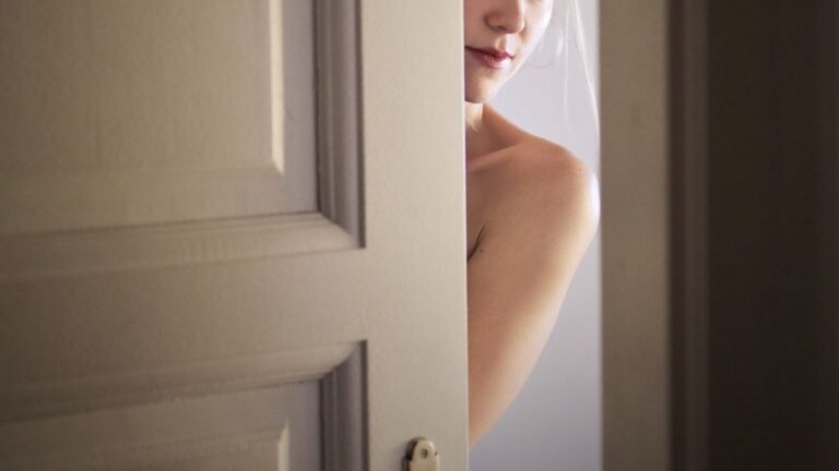 Het naakte lichaam van een vrouw gluurt achter een deur