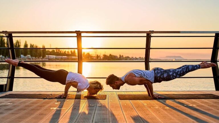 Koppel dat yoga doet met de zonsondergang in de achtergrond.