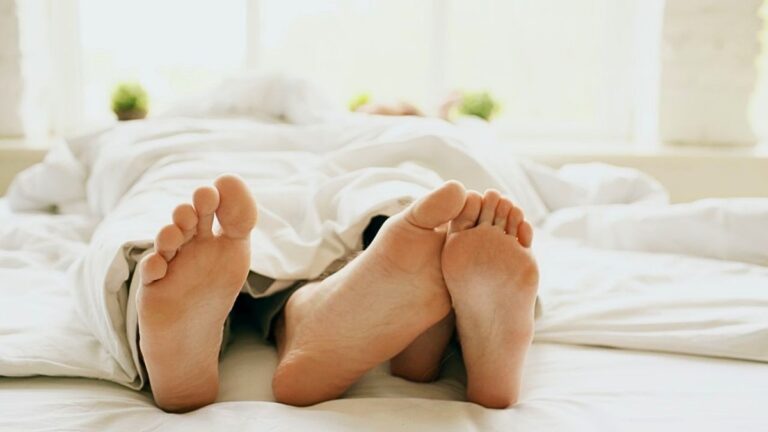 speelse voetjes van twee mensen die onder de dekens vandaan komen